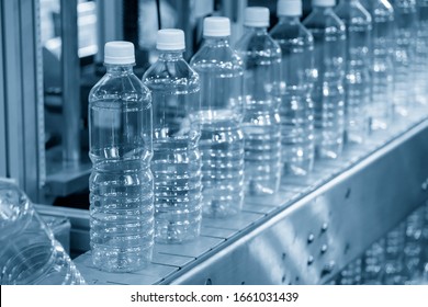 The PET bottles in the rail on the conveyor belt for filling process in the drinking water factory. The drinking water factory production process by automatic filling machine in the plant. 