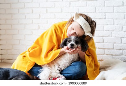 Pet care. Funny smiling young woman in yellow plaid sitting with her dogs reading a book