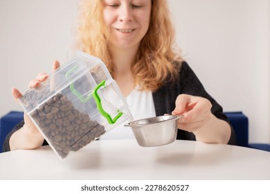 pet food, the owner pours dry dog food from the box into the dog bowl, cat feed - Powered by Shutterstock