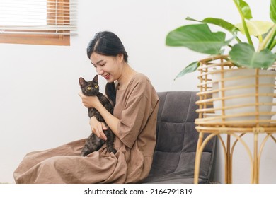 Pet Lover Concept, Young Asian Woman Sitting To Relax On Sofa On Floor To Playing And Hugging Cat.