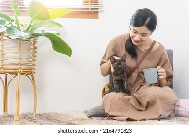 Pet Lover Concept, Young Asian Woman Relax With Drinking Coffee And Playing With Cat In Living Room.