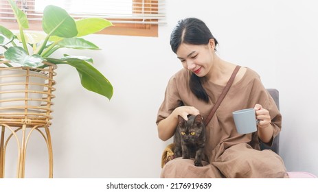 Pet Lover Concept, Young Asian Woman Relax With Drinking Coffee And Playing With Cat In Living Room.