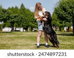 A pet owner plays fetch with their dog using a green flying disc in a park on a sunny day, bonding and having outdoor fun