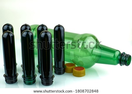 PET preforms and plastic bottle on white background. Brown and green PET preforms for plastic bottles