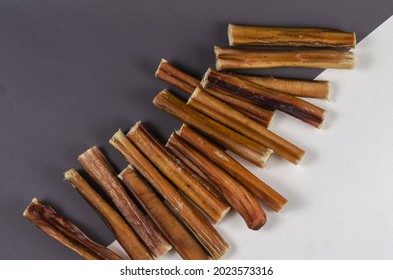 Pet treats. A group of brown treats on a gray and white background. 6-inch Bully sticks. Beef pizzle for dog. Natural air dried chewing sticks. Top view