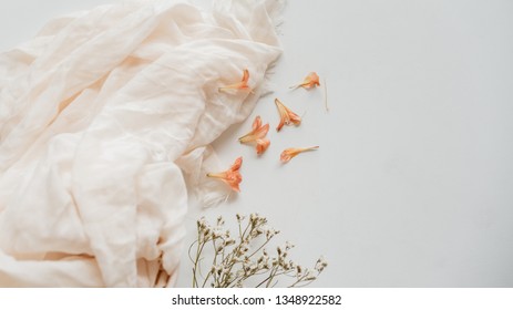Petals, textiles and flowers on a white surface.