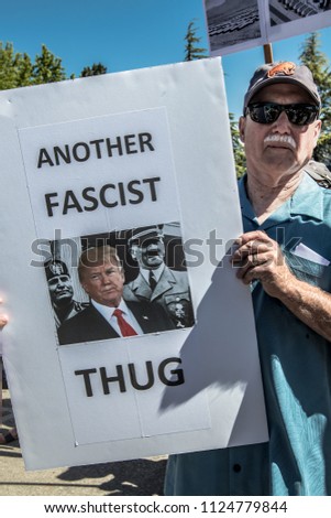 Petaluma, CA/USA-June 30, 2018: Man holds sign comparing President Trump with Hitler and Mussolini, calling them fascist thugs, during Keep Families Together March