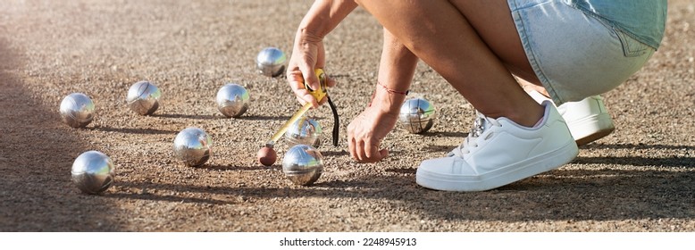 Petanque game, woman measuring the distance of petanque ball in petanque field, deciding who's the winner - Shutterstock ID 2248945913