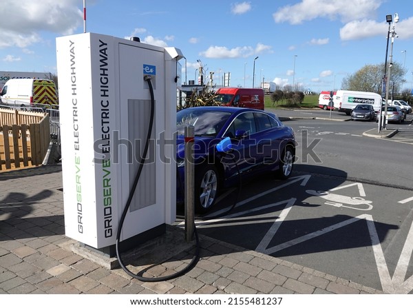 Peterborough, UK - March 14, 2022: An electric\
car plugged in to a Gridserve Electric Highway charging point at\
Peterborough services on the A1 in the\
UK.