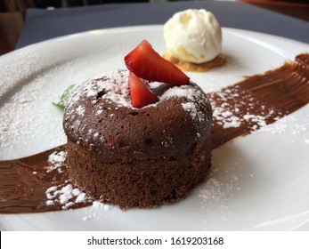 petit gâteau, chocolate fondant, dessert composed of a small chocolate cake with crunchy rind and mellow filling that is served hot with vanilla ice cream on a plate. - Shutterstock ID 1619203168