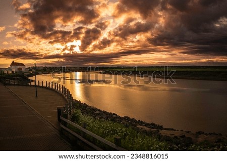 Petitcodiac River with dramatic sunrise cloudscape at Bore Park or Parc Bore Riverfront Walk, a popular place to watch the tidal bore in Moncton, New Brunswick, Canada