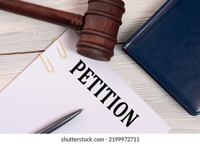 PETITION - word on a white sheet against the background of a judge's gavel, a notebook and a judge's pen. Business concept