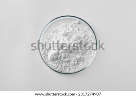 Petri dish with calcium carbonate powder on white background, top view