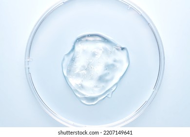 Petri dish with gel or cosmetic liquid on blue background closeup. Transparent container with gel with bubbles. Texture of the gel. Medicine and beauty concept. Medical glassware for laboratories - Shutterstock ID 2207149641