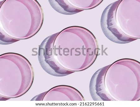 petri dish with liquid on plain pink background