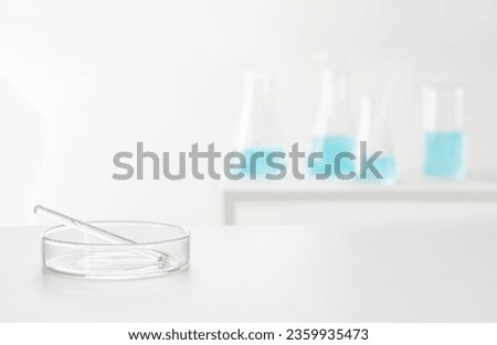 Petri dish and pipette on blurred background of laboratory glassware