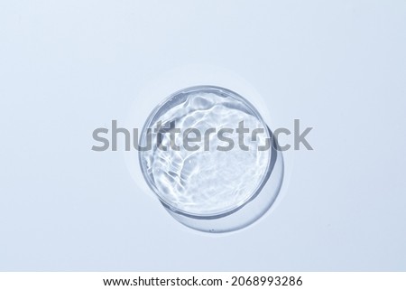 Petri dish with water and different ripple on baby blue background