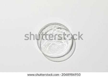 Petri dish with water and ripple in cream-colored background 
