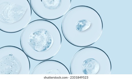 Petri dishes and drops and ointments of transparent gel or serum on a blue background. Banner with empty space for advertising. - Shutterstock ID 2331849523