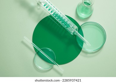 Petri dishes, test tube with spiral pipe and an erlenmeyer flask filled with green fluid. Vacant space on the plastic board to show your product