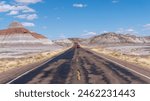 Petrified Forest National Park in Arizona. Car traveling on Petrified Forest Road through The Tepees, conical hills with banded mudstones resembling Tipis or Male Hogans.