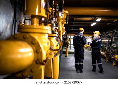 Petrochemical industry, oil and gas production. Factory workers or engineers walking by gas pipelines inside refinery production plant. - Shutterstock ID 2162729077