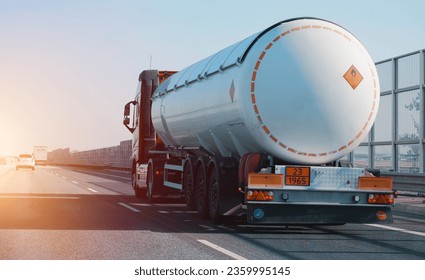 Petrol cargo truck driving on highway hauling oil products. Fuel delivery transportation and logistics concept on a sunny summer evening. Compressed gas carrier truck rear view on a highway.