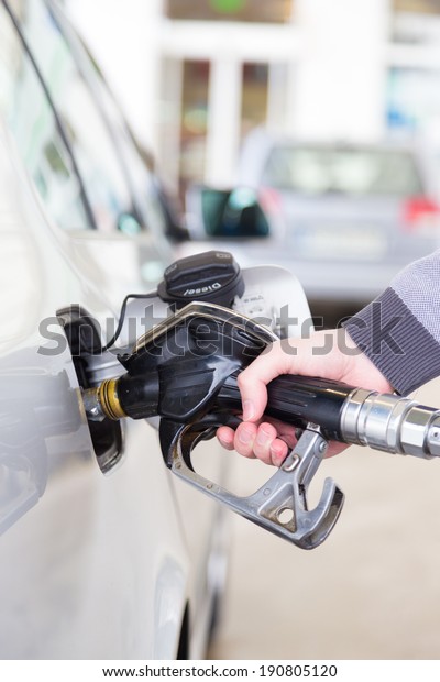 Petrol or\
gasoline being pumped into a motor vehicle car. Closeup of man\
pumping gasoline fuel in car at gas\
station.