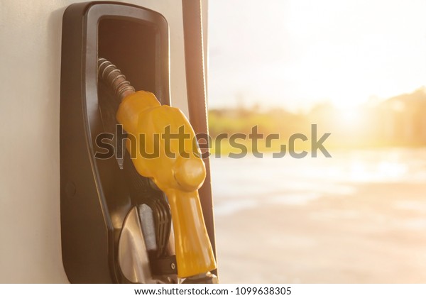 Petrol pump filling nozzles yellow background ,\
Gas station in sunset\
evening