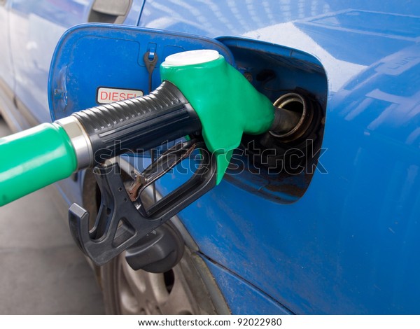 petrol pump nozzle is\
filling up blue car