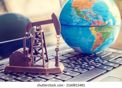 Petroleum and crude oil concept : Oil rig or a pumpjack and world globe on a laptop, depicting investment and development or production and manufacturing of global oil industry around the world. - Shutterstock ID 2160815481