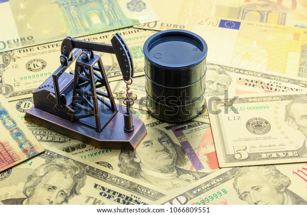 Petroleum, petrodollar and crude oil concept :\
Pump jack and a black barrel on US USD dollar notes, depicts the\
money received or earned from sales after investment in the\
development of oil\
industry.