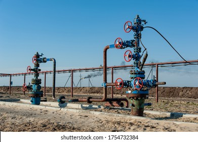 Petroleum well wellhead equipment. Hand valve with handwheel on the flow line. Oilfield site. Oil, gas industry concept. Industrial site background. Production oil. Multiple check valve gate armature.