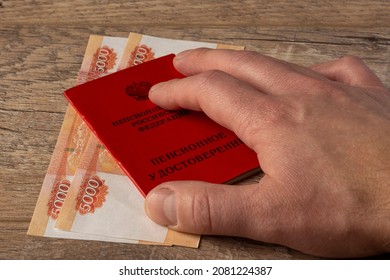 Petrozavodsk, Russia 11.18.2021. Human Hand On Labor Veteran Identity Document, Pension Cash Money