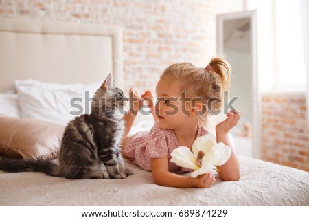 Pets, morning, comfort, rest and people concept - happy little girl with cat in bed at home