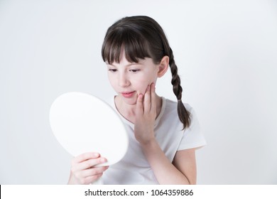 Petty girl checking her favial skin with a hand mirror.