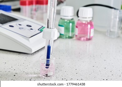 PH Meter With Glass Electrode For Measuring Of Alkalinity And Acidity With Calibration Solution On The Background. Analytical Or Electro Chemistry Laboratory