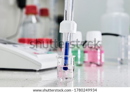 pH meter with glass electrode for measuring of alkalinity and acidity with calibration solution on the background. Analytical or electro chemistry laboratory