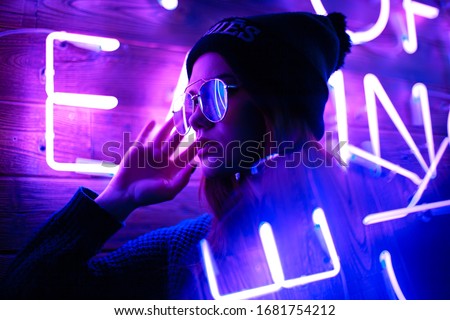 Phantom blue 2020 Trend.Portrait of a girl on the background of a neon sign of a shop window 