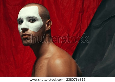 Phantom of the opera concept. Arty portrait of circus performer over red and black cloth background. White mask on face. Muscular body and perfect tan. Close up. Text space. Studio shot