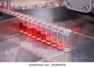 Pharmaceutical Automatic Production Line Machine Conveyor With Glass Bottles With Red Liquid At Pharmacy Processing Factory - Close Up. Pharma, Medicine, Vaccination, Automated Technology Concept