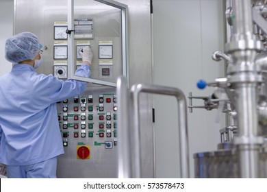 Pharmaceutical And Medicine Manufacturing. Female Worker Operating Control Panel Of The Pharmaceutical Machine. Biomedical And Pharmaceutical Research.Female Science Researcher In Protective Uniform.