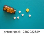 Pharmaceutical medicine pills or tablets with brown glass jar on blue paper, white and yellow pills background, health care concept, copy space, place for text. Pill bottle. Selective focus, top view