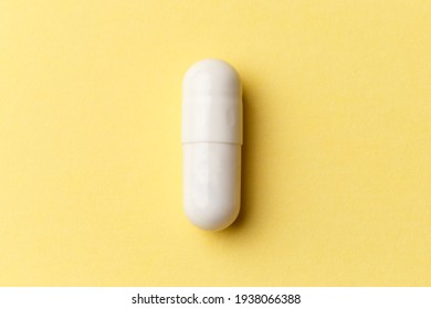 Tabletten, Tabletten und Kapseln des Arzneimittels auf buntem gelbem Hintergrund. Draufsicht. Flat lay. Kopiert Platz. Medizinische Konzepte. Minimalistisches abstraktes Konzept. Weiße Kapsel
