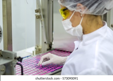 Pharmaceutical Production Line. An Employee Oversees The Packaging Of The Medical Pills. Pharmaceutical Manufacturing Technician Wearing Protective Clothing. 