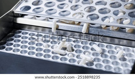 Pharmaceutical production line white capsules moving on conveyor.
