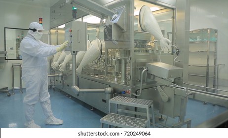 Pharmaceutical Production Line Worker at Work. Robotic arm lifting ampules at packaging line in pharmaceutical factory. Pharmaceutical industry. Ampule packaging machine