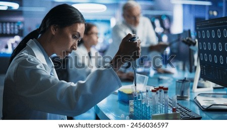 Pharmaceutical Research Laboratory: Female Asian Doctor Working With Test Tubes To Study Innovative Mental Disorder Medicine. Focus Shifting To Caucasian Colleague Looking At CT Brain Scan On Computer
