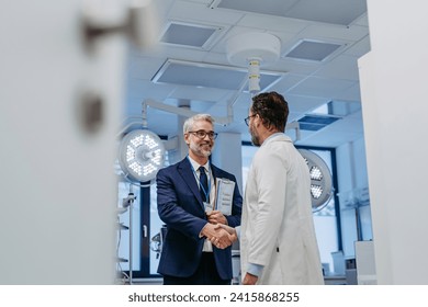 Pharmaceutical sales representative presenting new medication to doctor in medical building, shaking hands. Through door. - Powered by Shutterstock