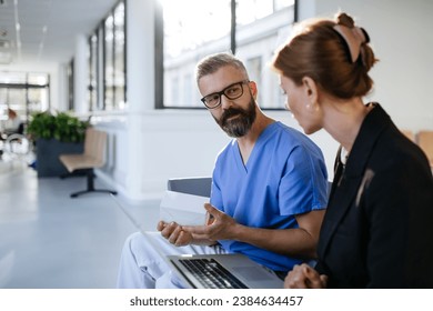 Pharmaceutical sales representative talking with doctor in medical building. Ambitious female sales representative presenting new medication. Woman business leader.